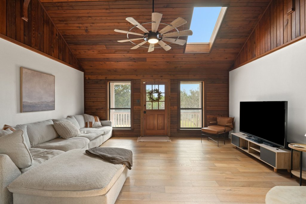 201 Raincloud Road Wimberley, TX 78676 - Photo 7 of 40 Living area with ceiling fan, light wood-type flooring, wooden walls, a vaulted wood ceiling, and a skylight
