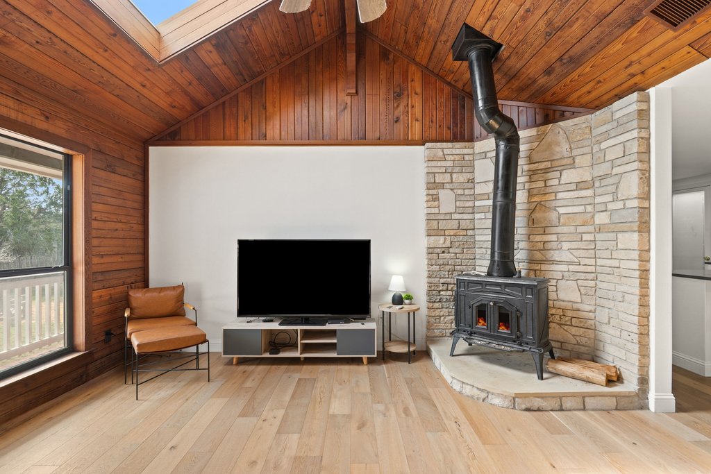 201 Raincloud Road Wimberley, TX 78676 - Photo 8 of 40 Living area featuring a vaulted wood ceiling, light wood-style flooring, a wood stove, a skylight, and ceiling fan