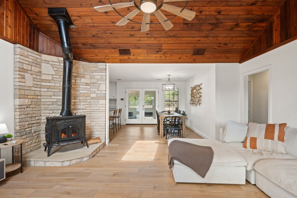 201 Raincloud Road Wimberley, TX 78676 - Photo 9 of 40 Living room featuring french doors, light wood-type flooring, a ceiling fan, a vaulted wood ceiling, and a wood stove