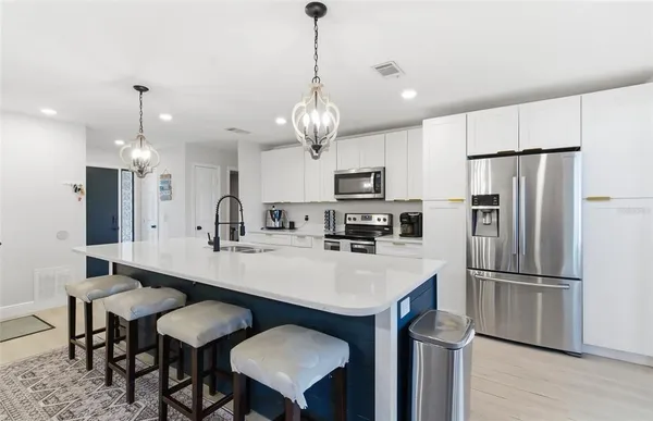 a kitchen with stainless steel appliances a table chairs stove microwave and refrigerator