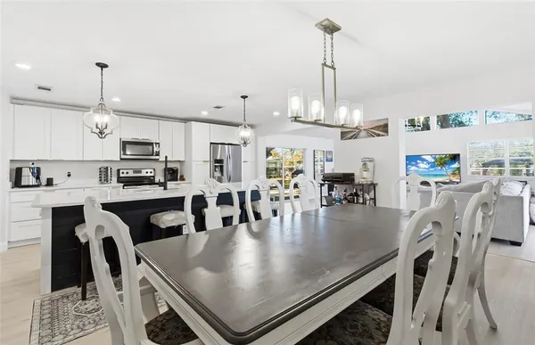 a kitchen with stainless steel appliances granite countertop a stove a refrigerator a kitchen island a dining table and chairs