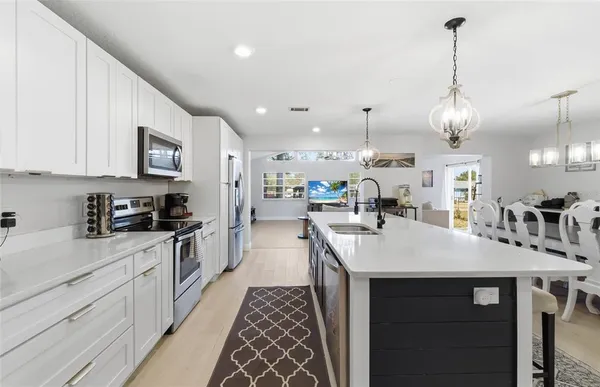 a kitchen with stainless steel appliances granite countertop a sink a stove top oven a chimney and a center island