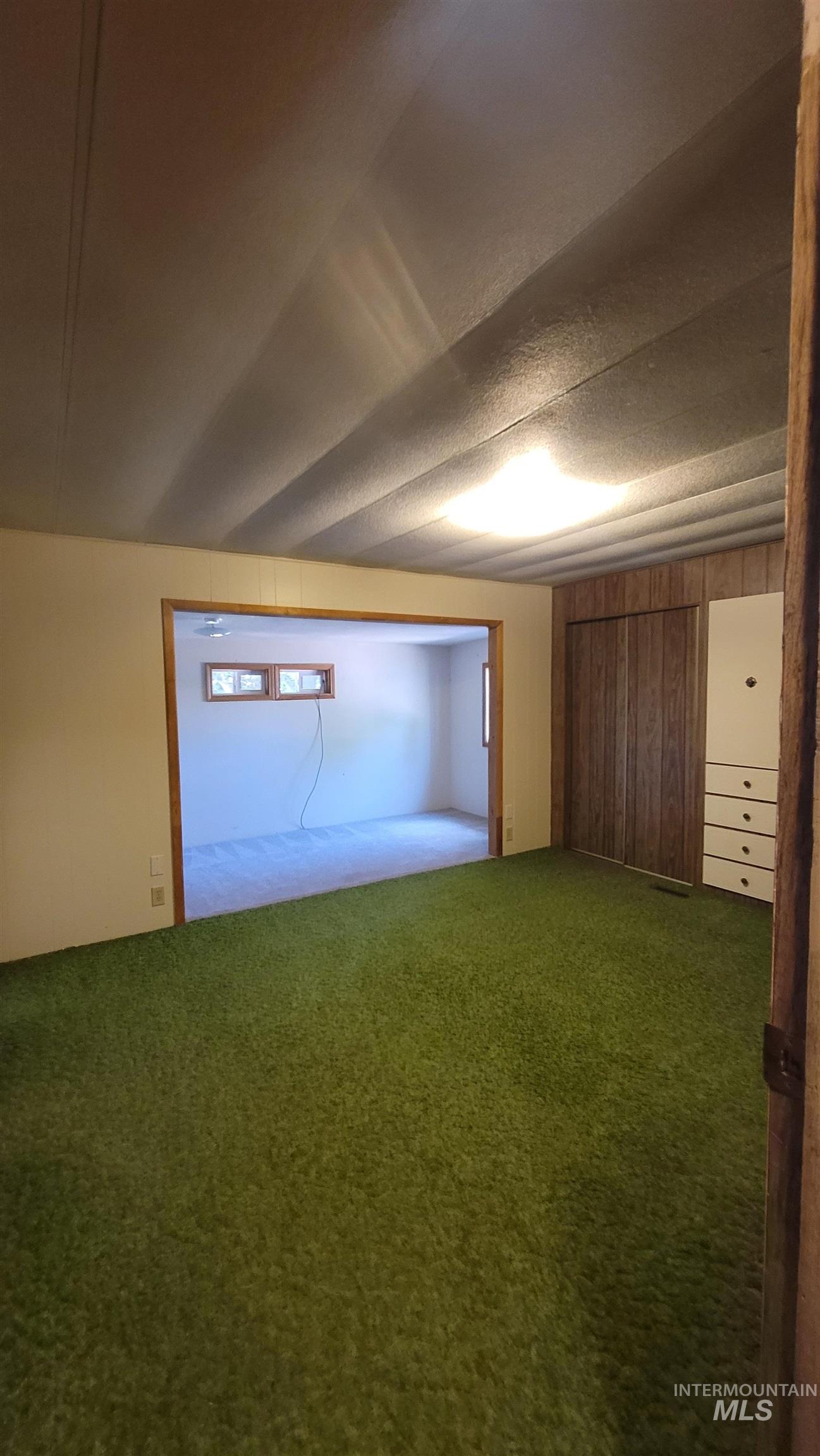 2122 Highway 95 Council, ID 83612 - Photo 19 of 31 Unfurnished bedroom featuring wooden walls, carpet flooring, and a textured ceiling