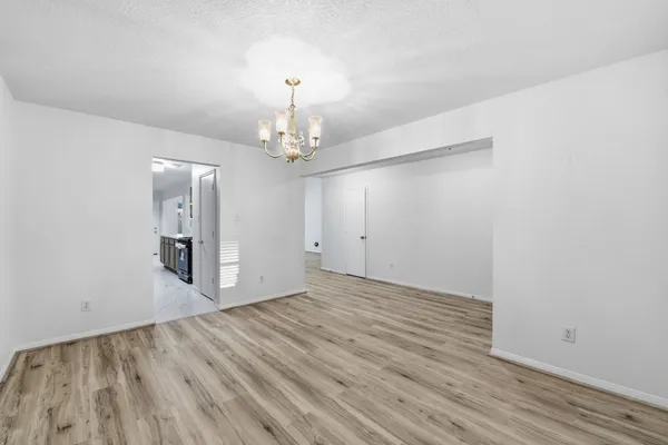 a view of empty room with wooden floor and chandelier