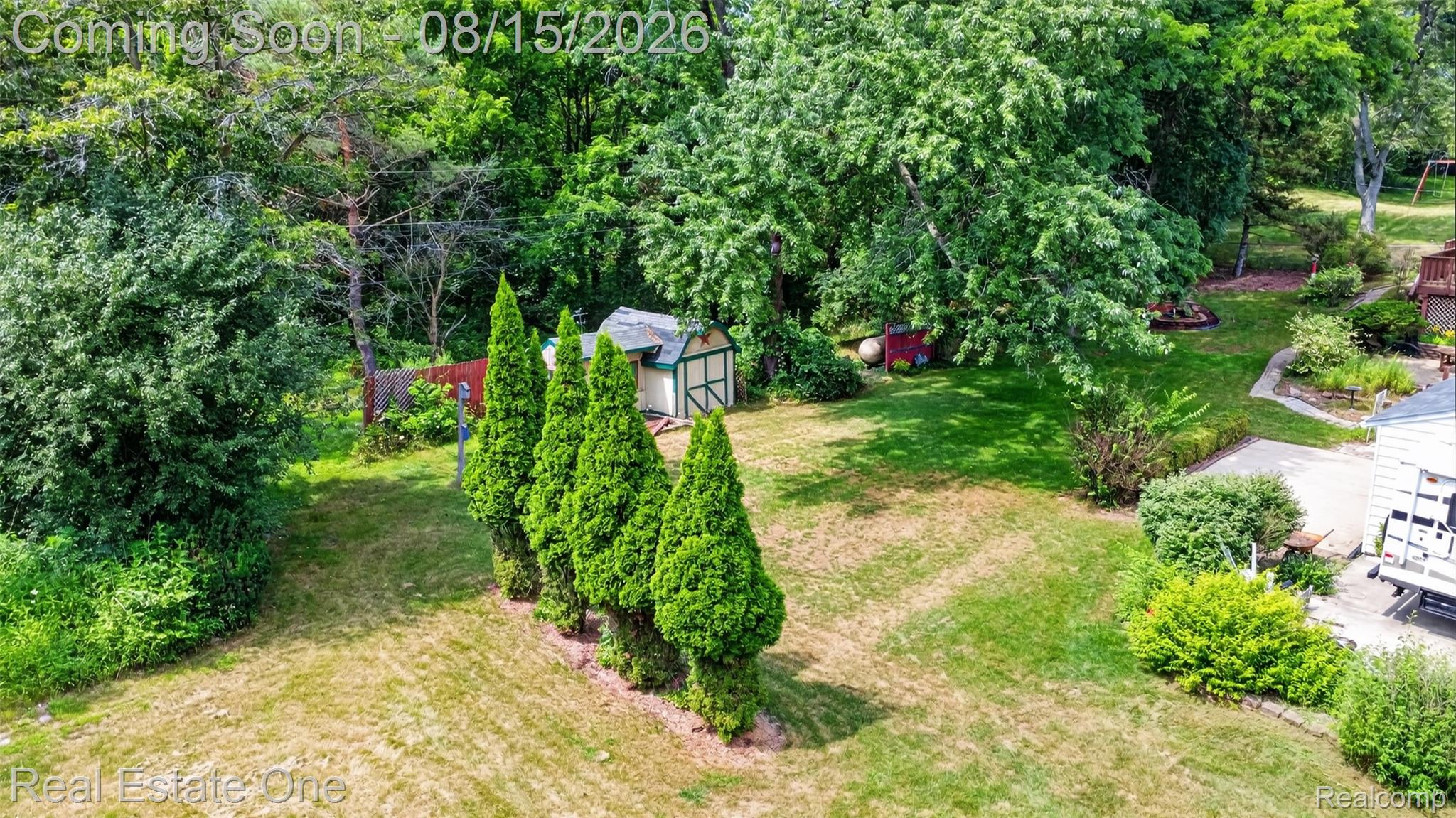 454 South Baldwin Road Oxford, MI 48371 - Photo 57 of 64 Expansive backyard featuring a row of columnar evergreens, mature trees, a detached shed, and a privacy fence