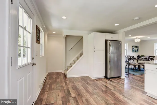 a view of empty room with wooden floor and a kitchen