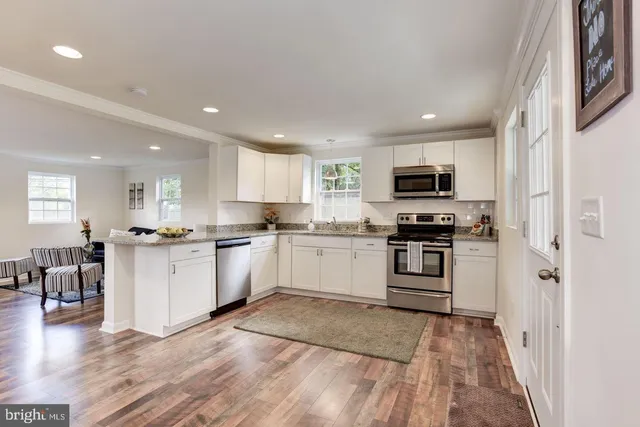 a kitchen with white cabinets stainless steel appliances and wooden floor