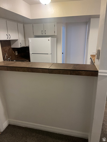 1175 Canyon Road, Unit A 5 Ogden, UT 84404 - Photo 10 of 15 Kitchen featuring white cabinetry, a built-in sink, a refrigerator, and a tiled breakfast bar