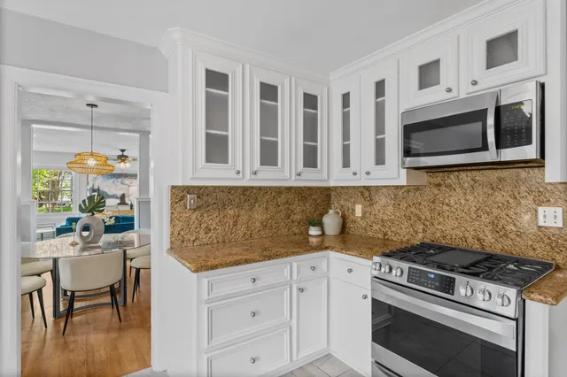 a kitchen with stainless steel appliances white cabinets and stove top oven