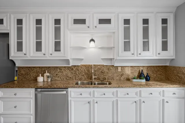 a kitchen with granite countertop white cabinets and stainless steel appliances