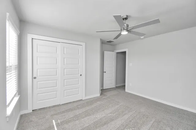 an empty room with a window and a fan