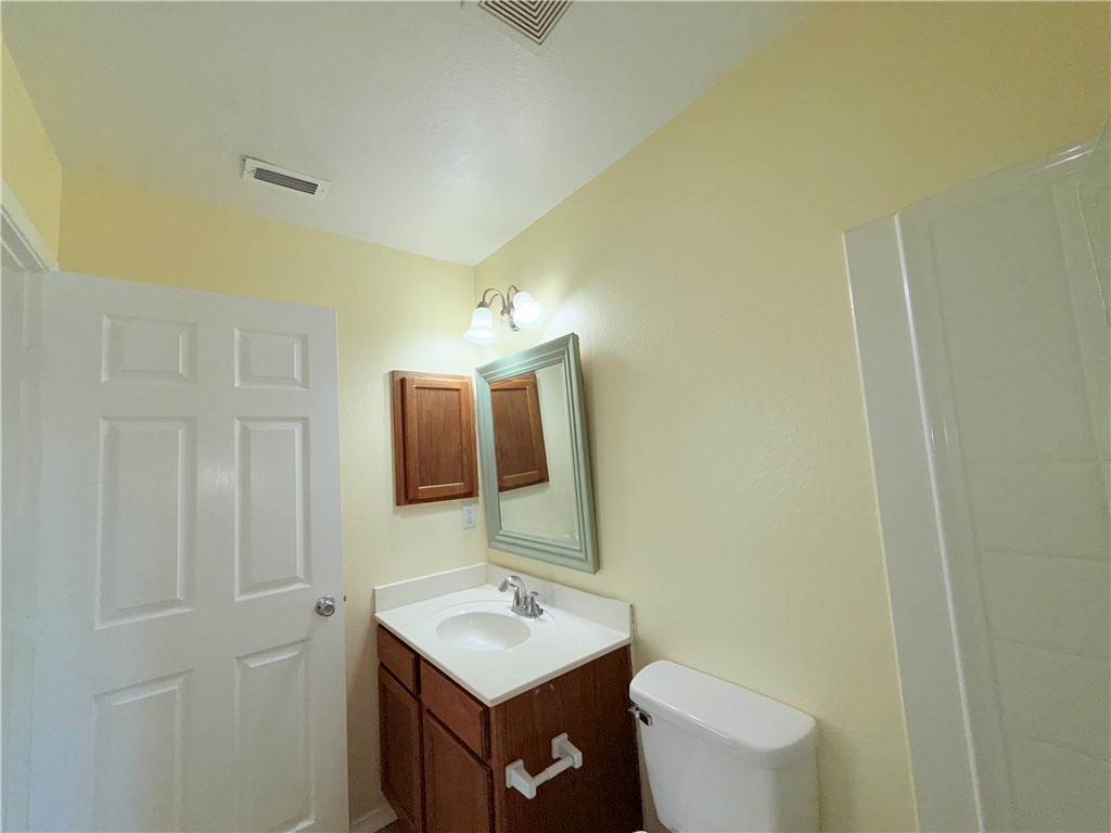 1019 Livermore Street Portland, TX 78374 - Photo 27 of 32 a bathroom with a toilet a sink and mirror