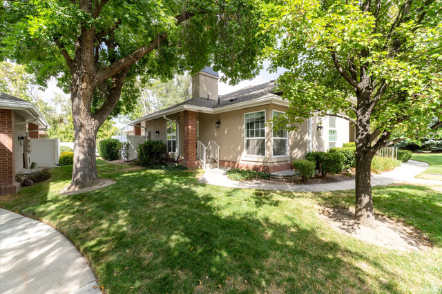 888 East 6895 South Midvale, UT 84047 - Photo 2 of 54 Exterior – Charming single-level exterior surrounded by mature trees and lush landscaping, offering shade, privacy, and a welcoming front entry with a peaceful, park-like setting.
