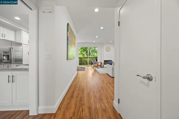 a view of a hallway with wooden floor and a bathroom