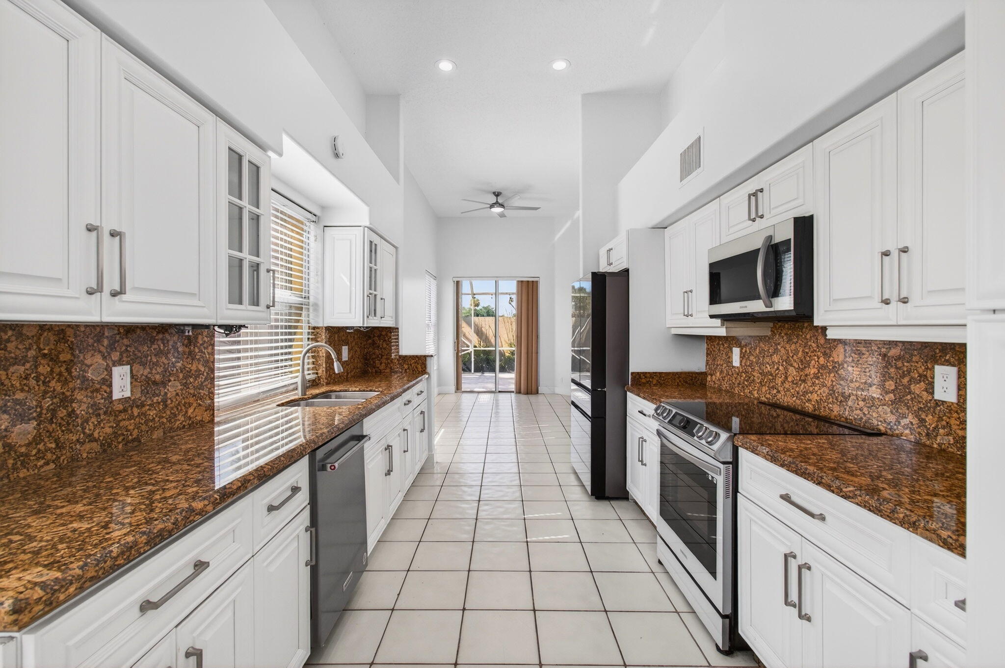 7848 Travelers Tree Drive Boca Raton, FL 33433 - Photo 18 of 60 a large kitchen with stainless steel appliances granite countertop a stove top oven a sink dishwasher a dining table and chairs with wooden floor