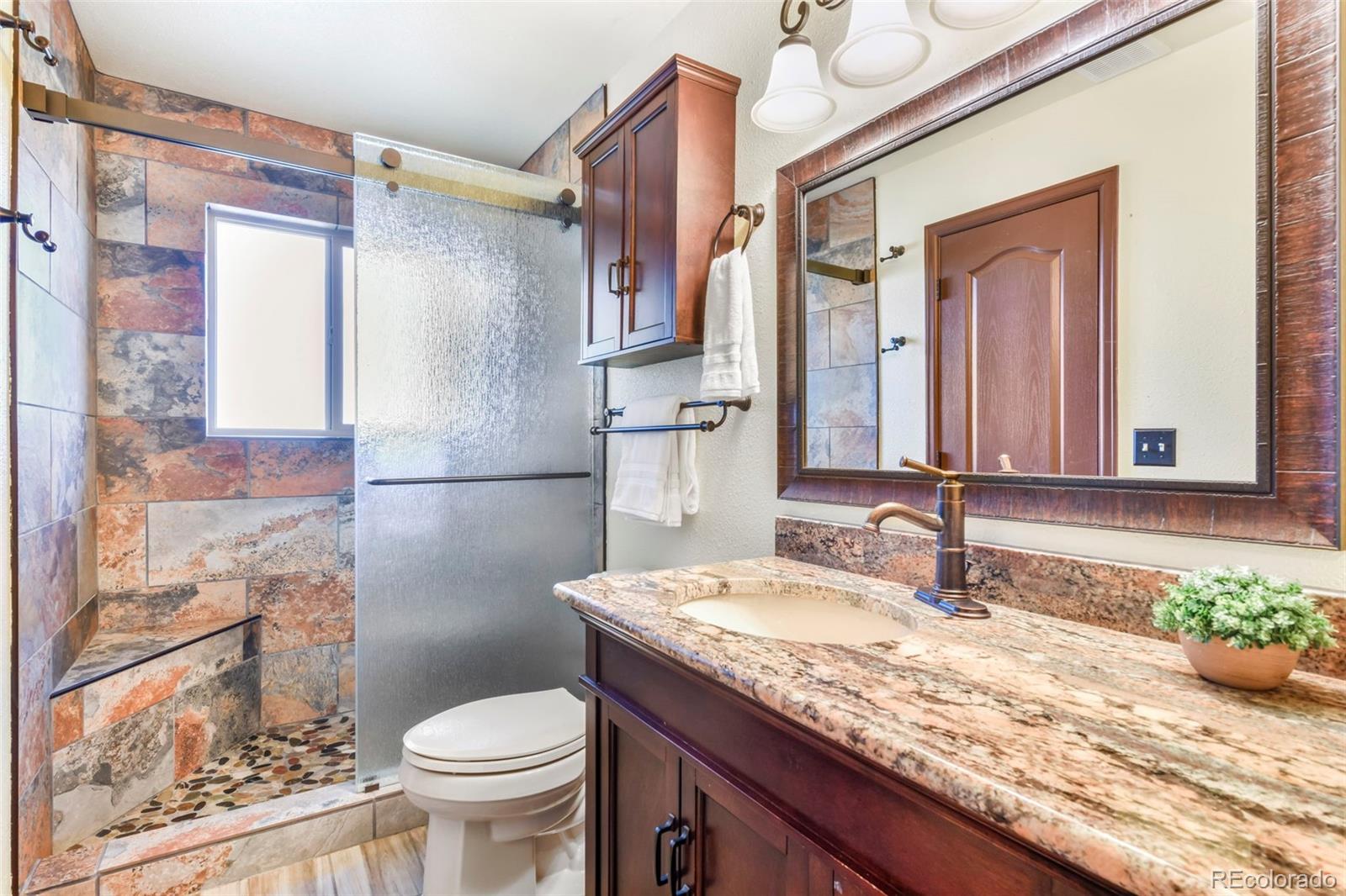 463 Washington Street Monument, CO 80132 - Photo 13 of 50 a bathroom with a granite countertop sink toilet and shower