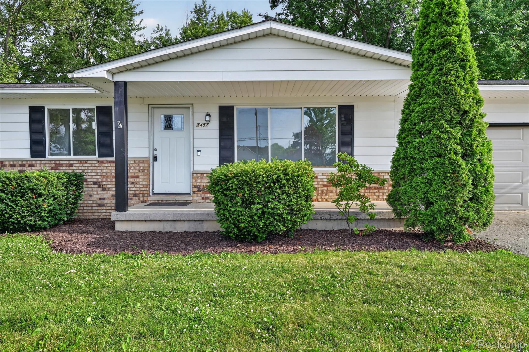 5457 Reid Road Swartz Creek, MI 48473 - Photo 7 of 51 Ranch-style exterior with white siding, brick accents, and black window shutters