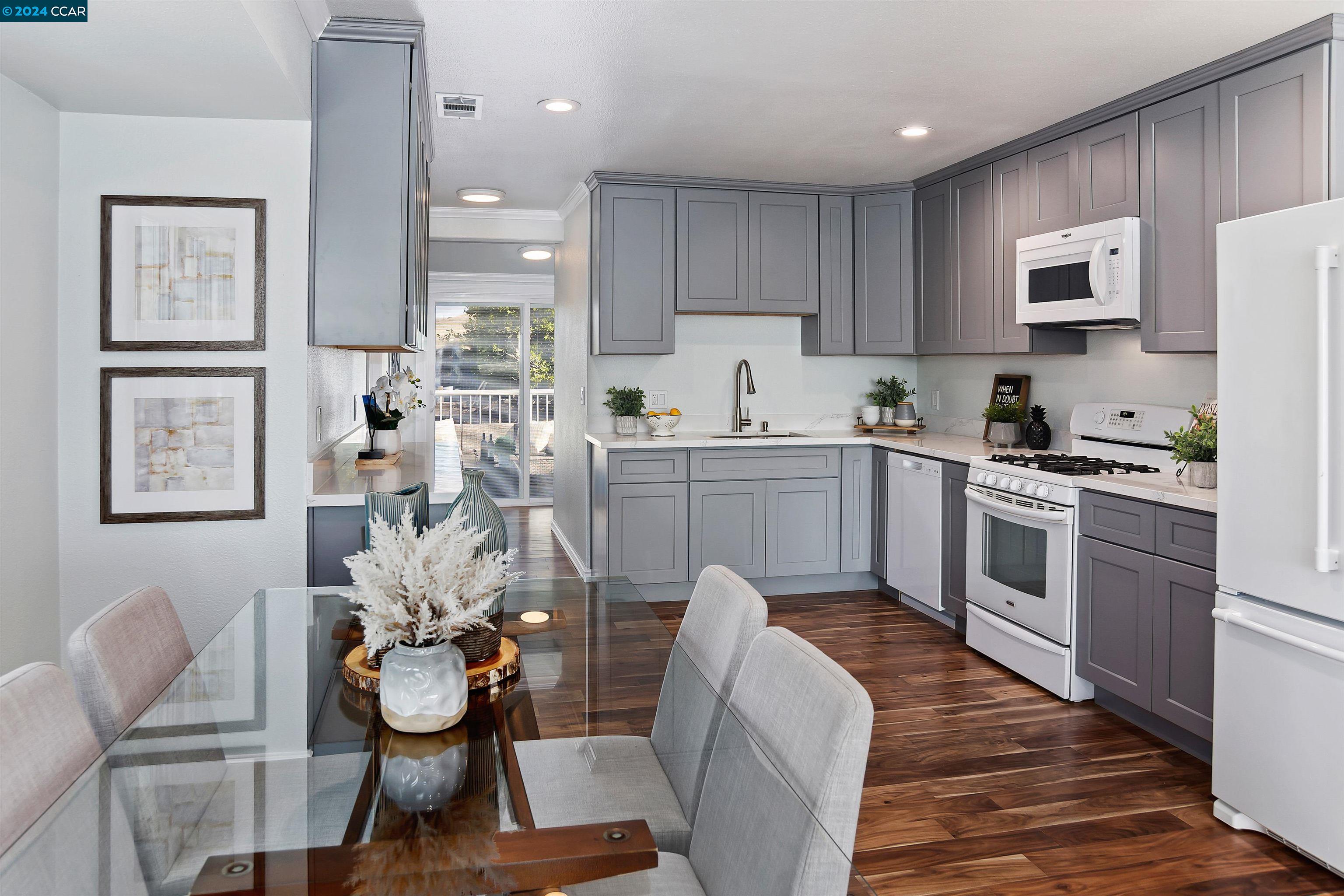 a kitchen with stainless steel appliances a stove a sink dishwasher a microwave oven and a dining table with wooden floor