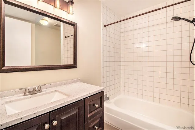 a bathroom with a granite countertop sink and a bathtub