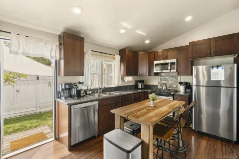 a kitchen with a refrigerator a stove a sink dishwasher with a dining table and chairs