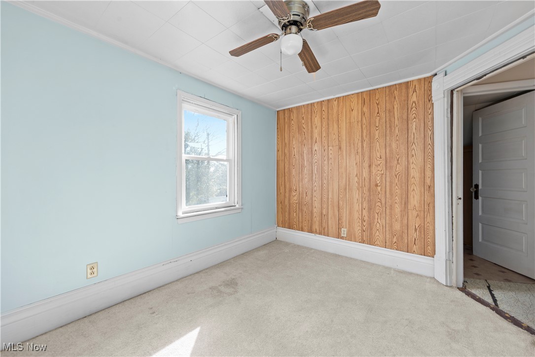 6927 North Wildacre Road Curtice, OH 43412 - Photo 28 of 44 Spare room featuring wood walls, carpet, and ceiling fan