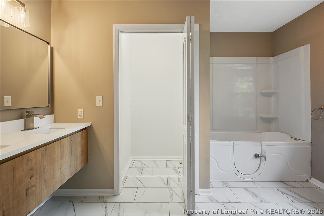 6062 Midus Street Hope Mills, NC 28348 - Photo 18 of 49 a bathroom with a granite countertop toilet a sink and shower