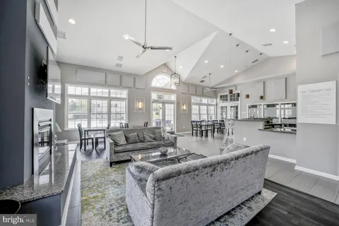 a living room with furniture kitchen area and a large window