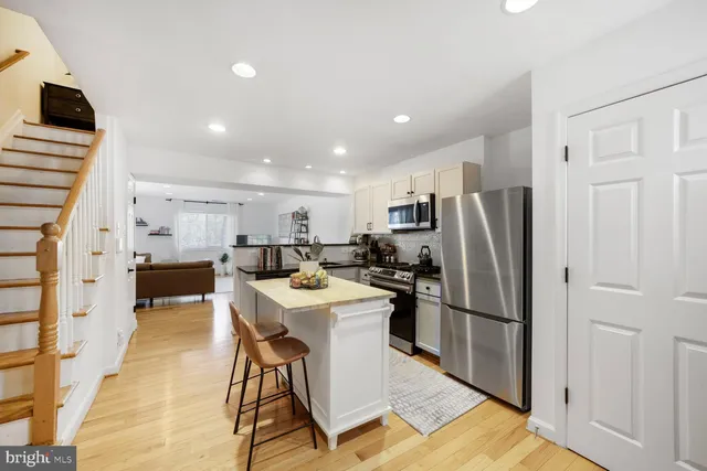 a kitchen with stainless steel appliances a refrigerator a stove a sink dishwasher and a refrigerator with wooden floor