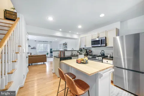 a kitchen with a refrigerator a stove and a dining table with wooden floor
