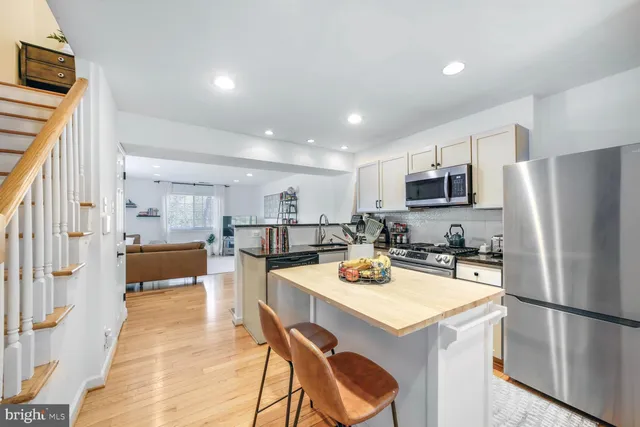 a kitchen with a refrigerator a stove and a dining table with wooden floor