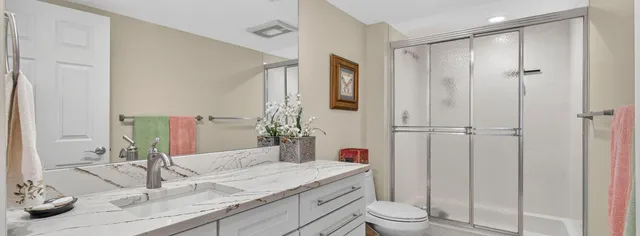 a bathroom with a granite countertop sink toilet and shower