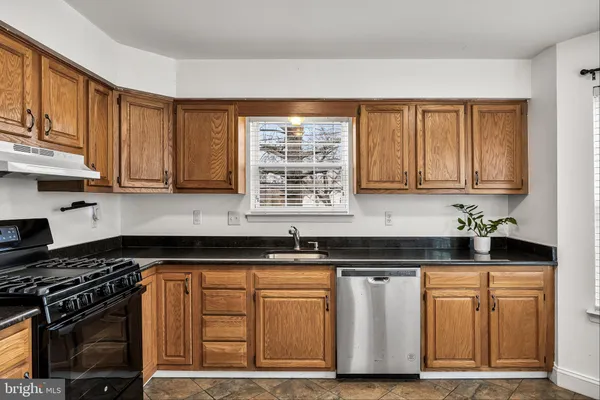 a kitchen with granite countertop a sink stove and cabinets