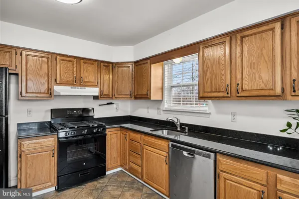 a kitchen with granite countertop a sink cabinets stainless steel appliances and a window