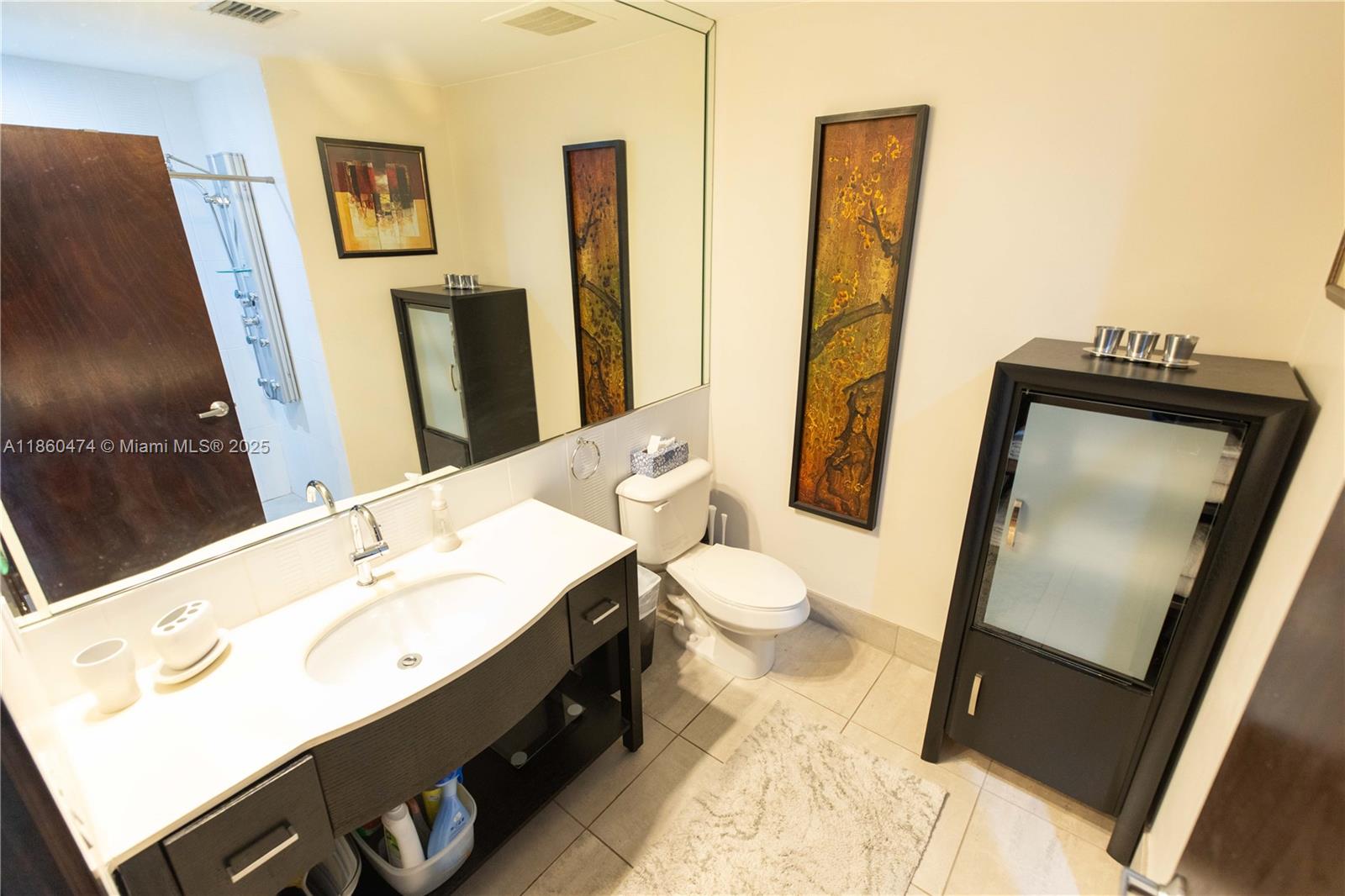 3250 Grand Avenue, Unit 404 Miami, FL 33133 - Photo 6 of 17 a bathroom with a sink a toilet and mirror
