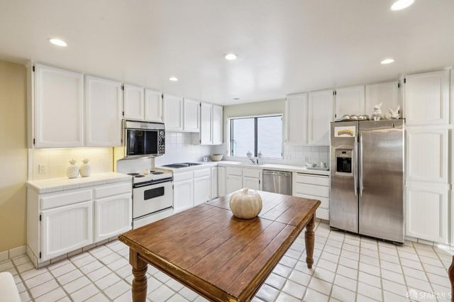 a kitchen with white cabinets and stainless steel appliances