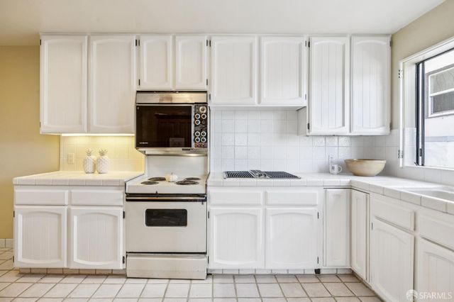 a kitchen with white cabinets and white appliances