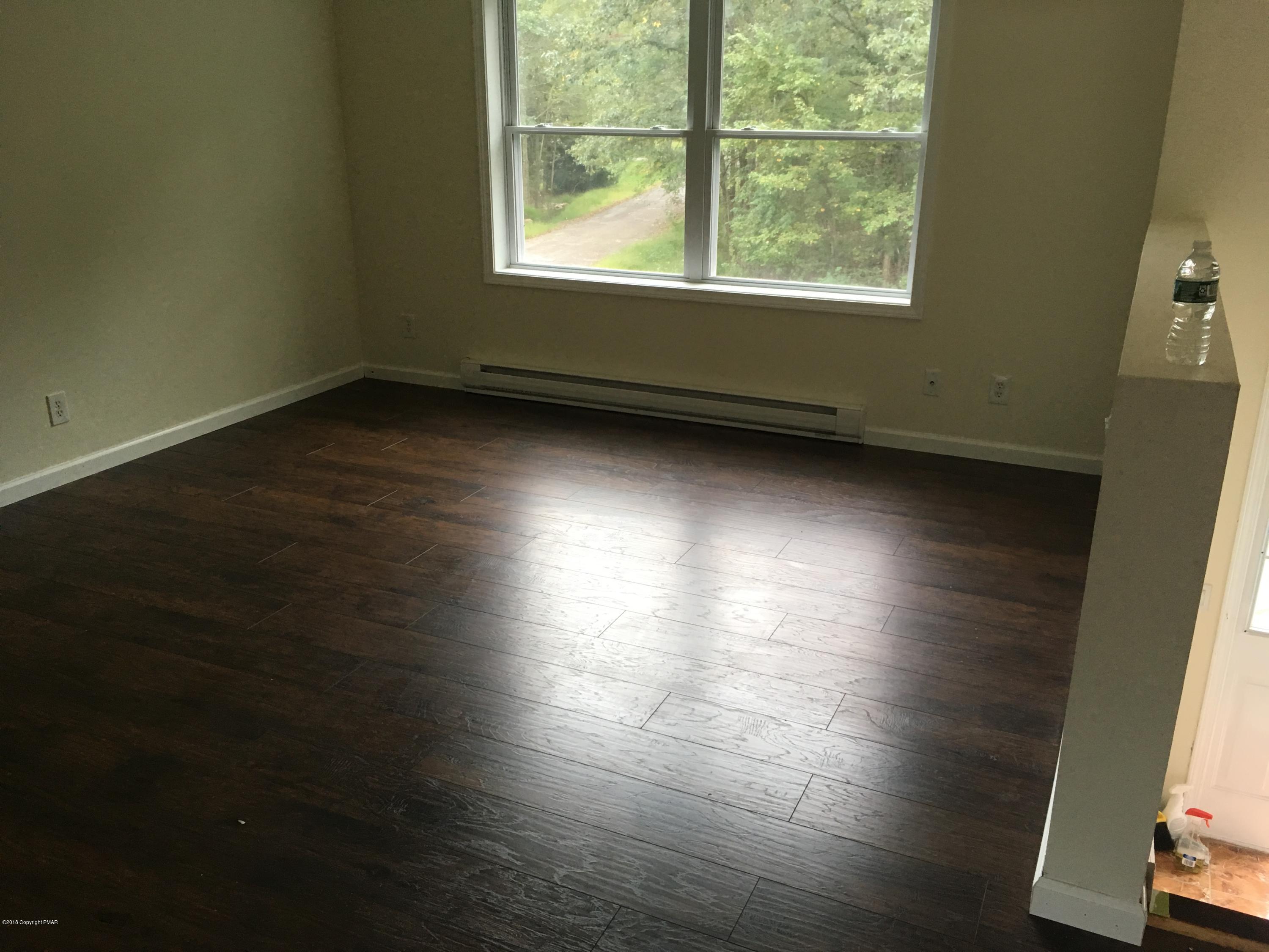 157 Magic Mountain Road Henryville, PA 18332 - Photo 14 of 29 an empty room with wooden floor and windows