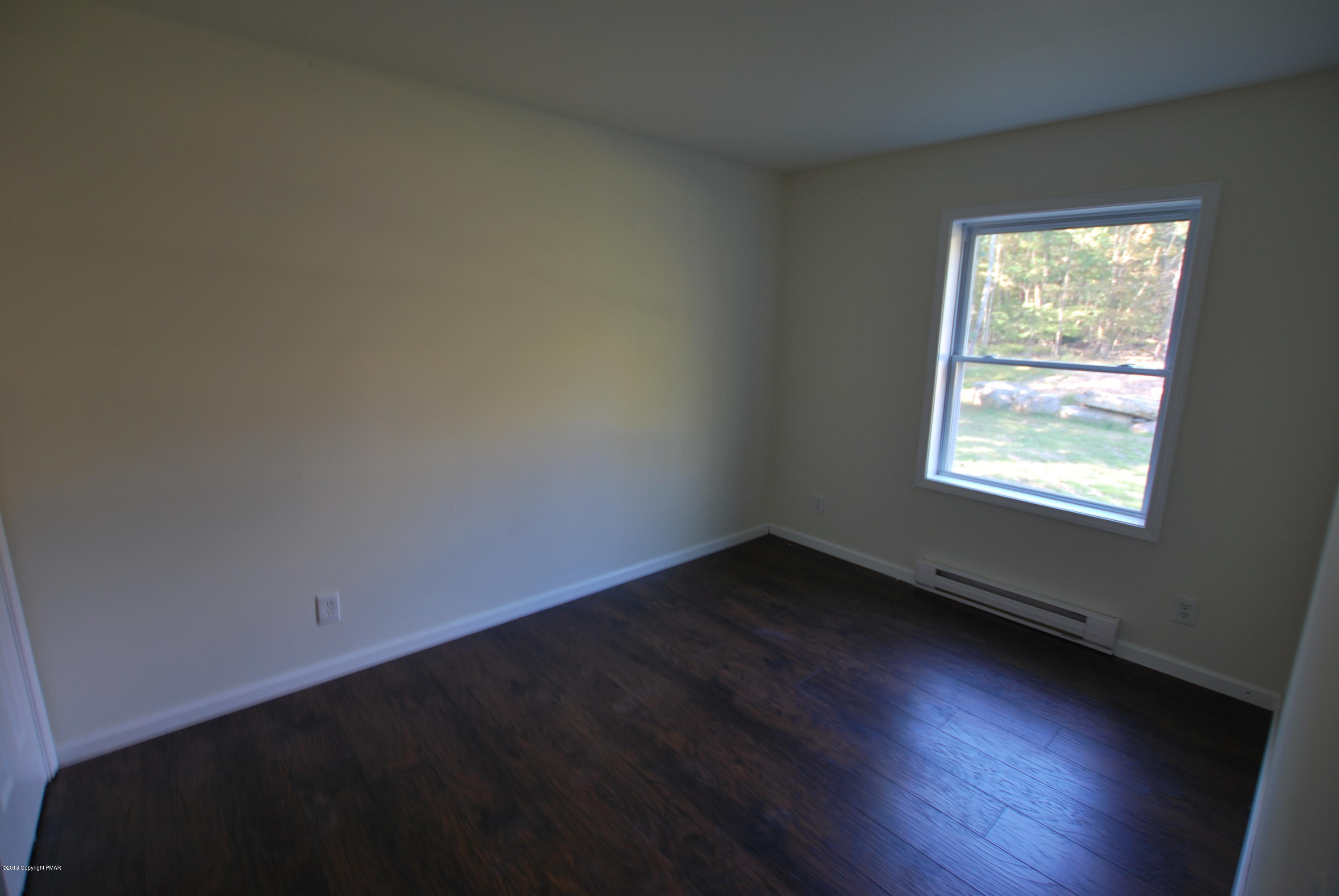 157 Magic Mountain Road Henryville, PA 18332 - Photo 26 of 29 an empty room with wooden floor and windows