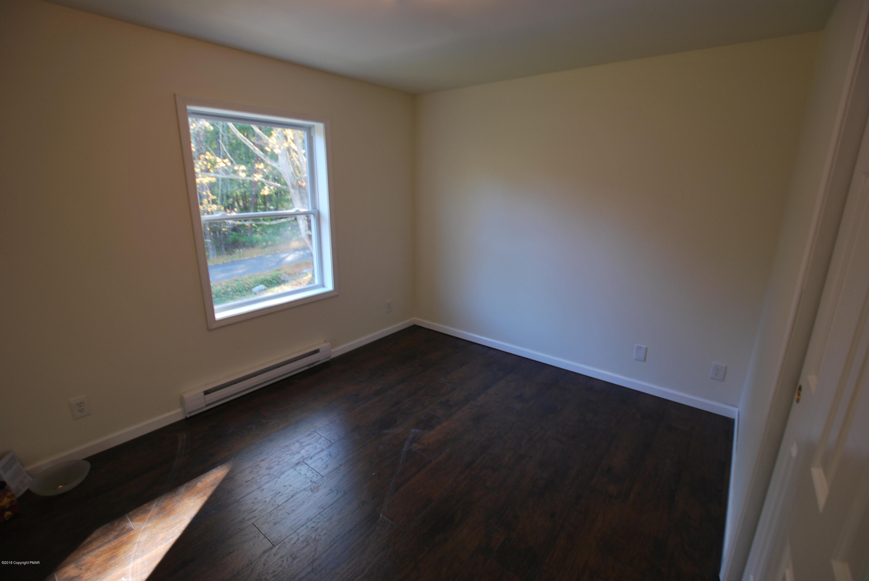 157 Magic Mountain Road Henryville, PA 18332 - Photo 27 of 29 an empty room with wooden floor and windows