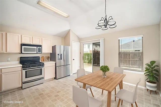 a kitchen with stainless steel appliances granite countertop a stove a refrigerator a kitchen island a table and chairs in it