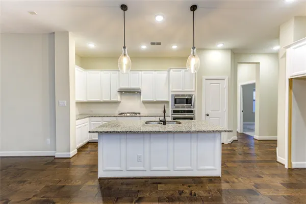 a kitchen with kitchen island a sink stove and wooden floor