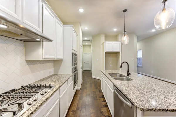a kitchen with kitchen island granite countertop a sink a counter space appliances and cabinets