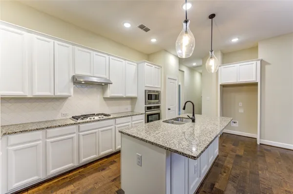 a kitchen with granite countertop kitchen island a sink appliances and a counter top space
