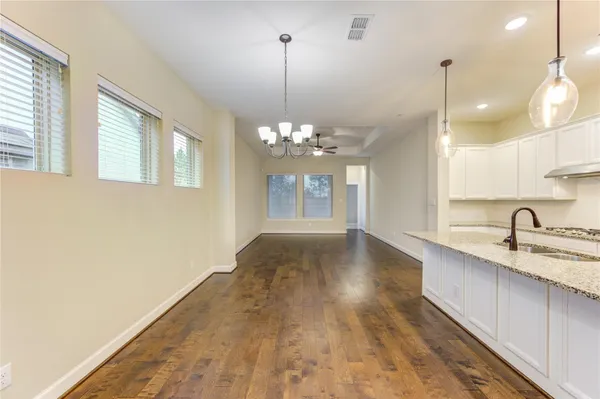 a kitchen with stainless steel appliances granite countertop a sink a refrigerator and a wooden floor