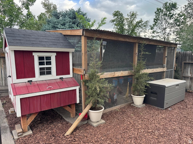 1791 West 170 South, Unit 8 Provo, UT 84601 - Photo 20 of 25 Red-painted chicken coop with white trim and a shingled roof, featuring an attached screened enclosure with a corrugated metal roof