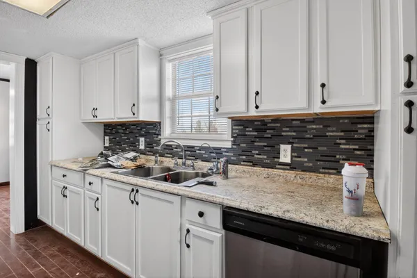 a kitchen with granite countertop a sink stove and cabinets