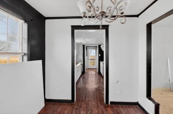 a view of a hallway with wooden floor and a large mirror