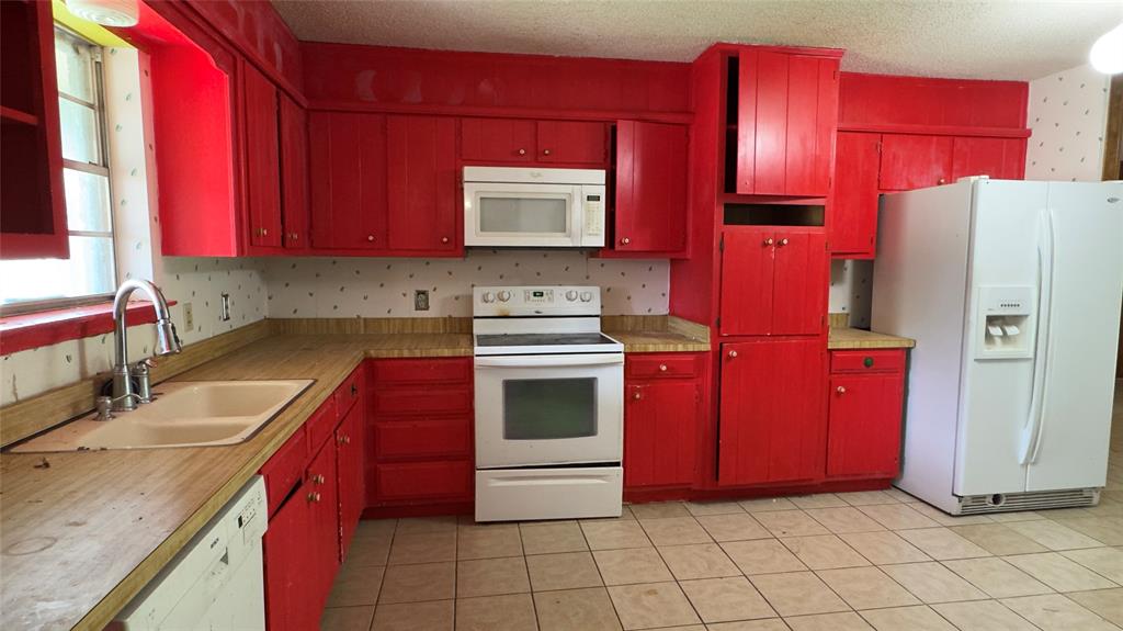 415 Meadowlark Trail Springtown, TX 76082 - Photo 6 of 35 a kitchen with stainless steel appliances granite countertop a stove top oven a sink dishwasher and a refrigerator with wooden cabinets