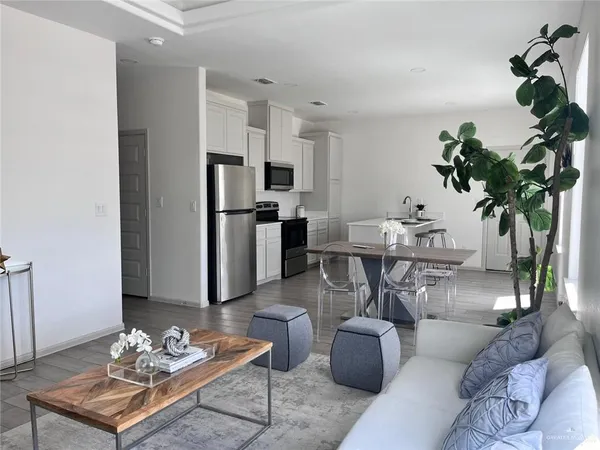 a living room with furniture potted plant and kitchen view