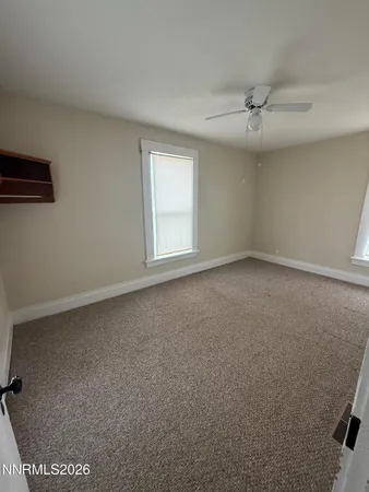 an empty room with a ceiling fan and window